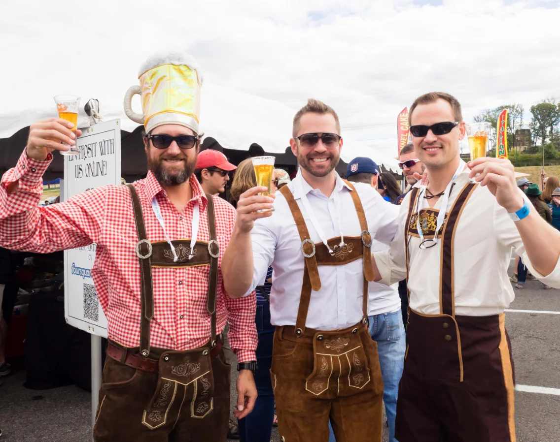Three guests in lederhosen toasting at an Oktoberfest event
