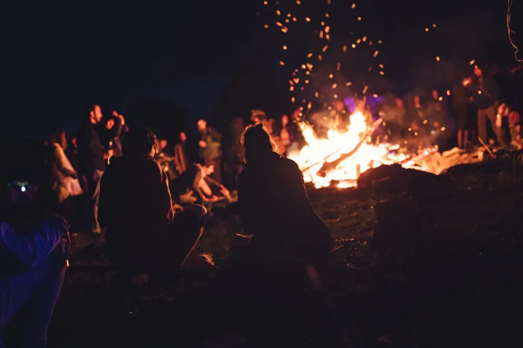 Guests gathered around a large bonfire at night