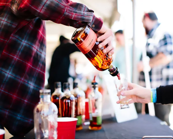Whiskey poured into a tasting glass at an outdoor festival bar